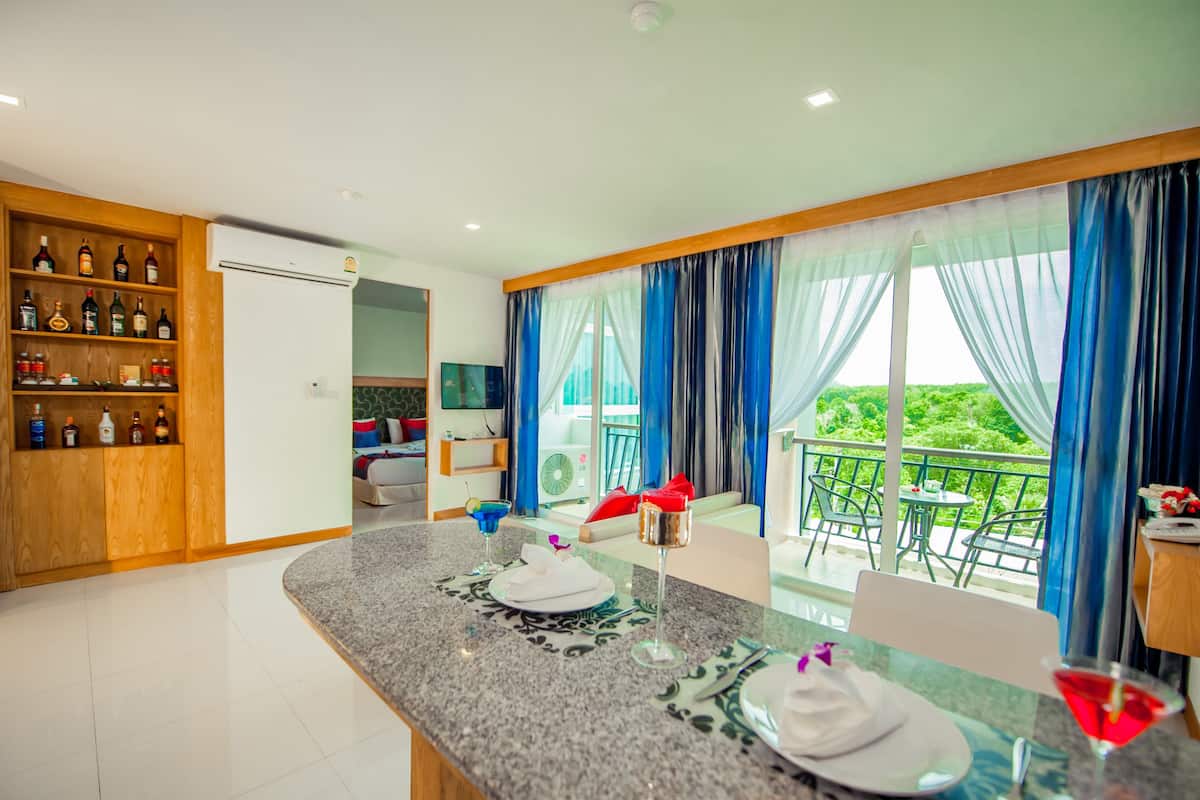 A hotel room with a balcony, a minibar, and a dining area.