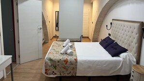 A bedroom with a bed, a bedside table, a wardrobe, and a mirror. - Living Sevilla Centro Maestranza (Seville)
