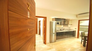 A modern kitchen with a stainless steel refrigerator, a microwave, and a sink. There is a wooden door with a brass handle and a number '2' on it. - Living Sevilla Centro Maestranza (Seville)