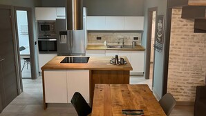 A modern kitchen with a central island, stainless steel appliances, and pendant lighting. - Living Sevilla Centro Maestranza (Seville)
