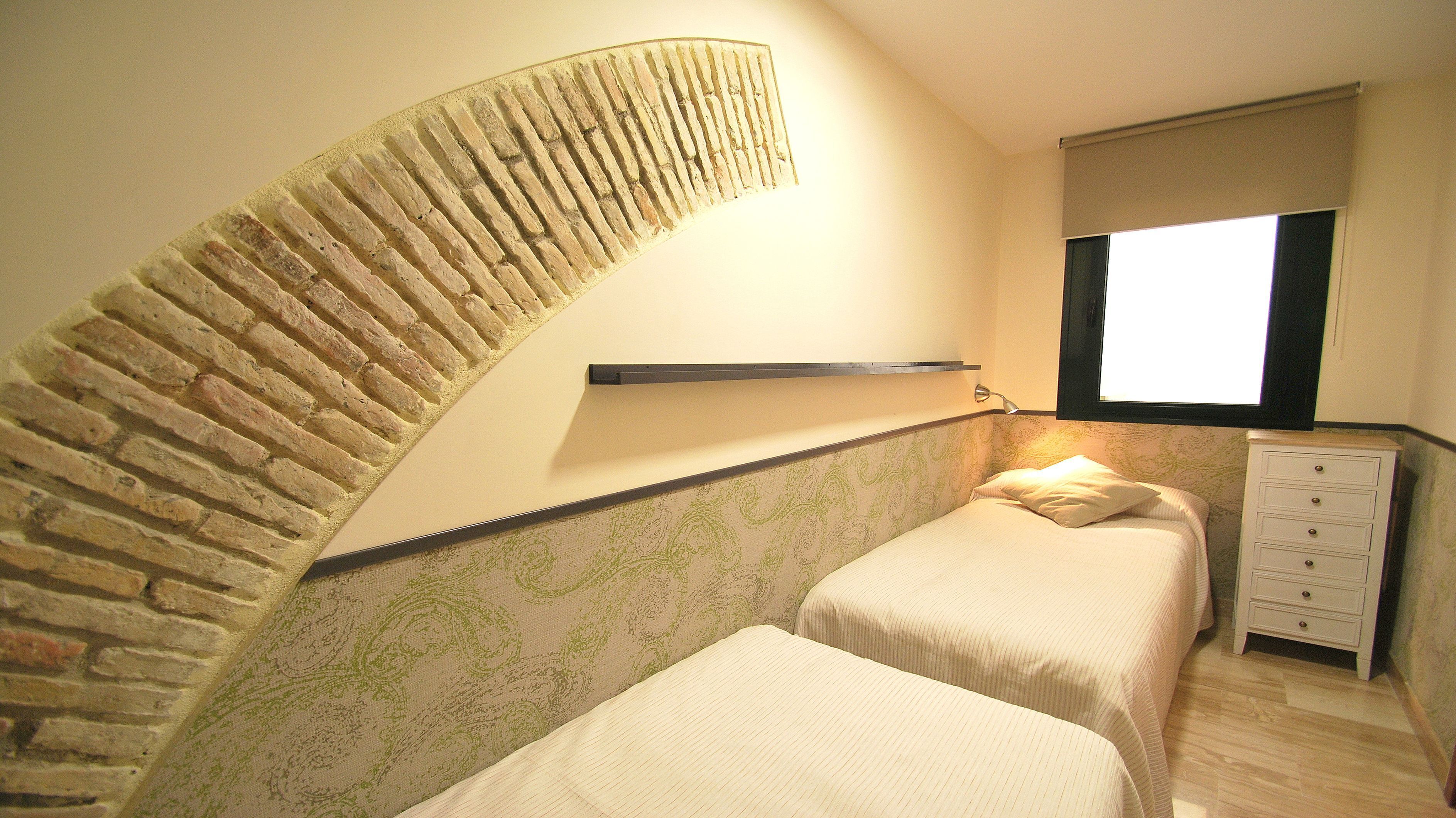 A bedroom with a curved wall, a bed, a nightstand, and a window.