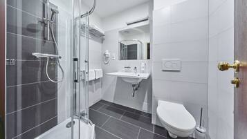 A modern bathroom with a glass-enclosed shower, a white sink, and a toilet.