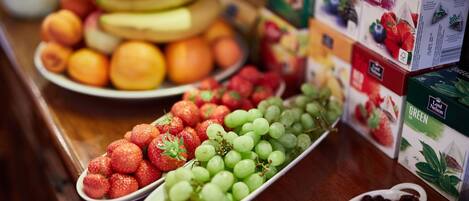 A variety of fresh fruits and packaged tea boxes on a wooden surface.