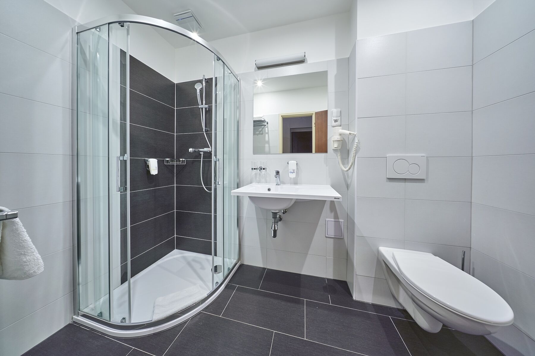 A modern bathroom with a glass-enclosed shower, a white sink, and a toilet.