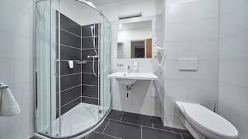 Une salle de bain moderne avec une douche à parois de verre, un lavabo blanc et des toilettes.