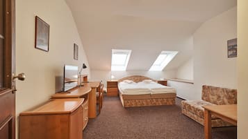 A bedroom with a bed, desk, chair, and a small table. There are skylights on the ceiling.
