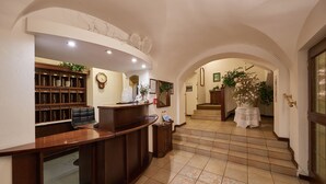 Un'area reception con una scrivania in legno, una libreria e una scala che conduce in un'altra stanza.