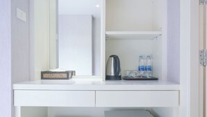 A white desk with a mirror, a tissue box, a kettle, and two water bottles.