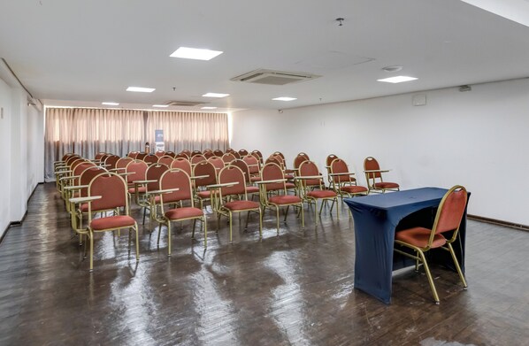A conference room with rows of chairs, a table, and a curtain backdrop.
