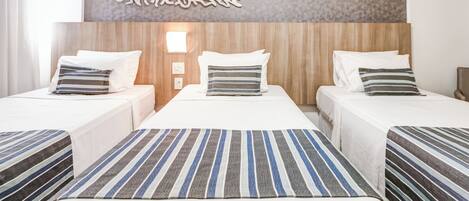 A hotel room with two beds, a decorative wall piece, and a light fixture.