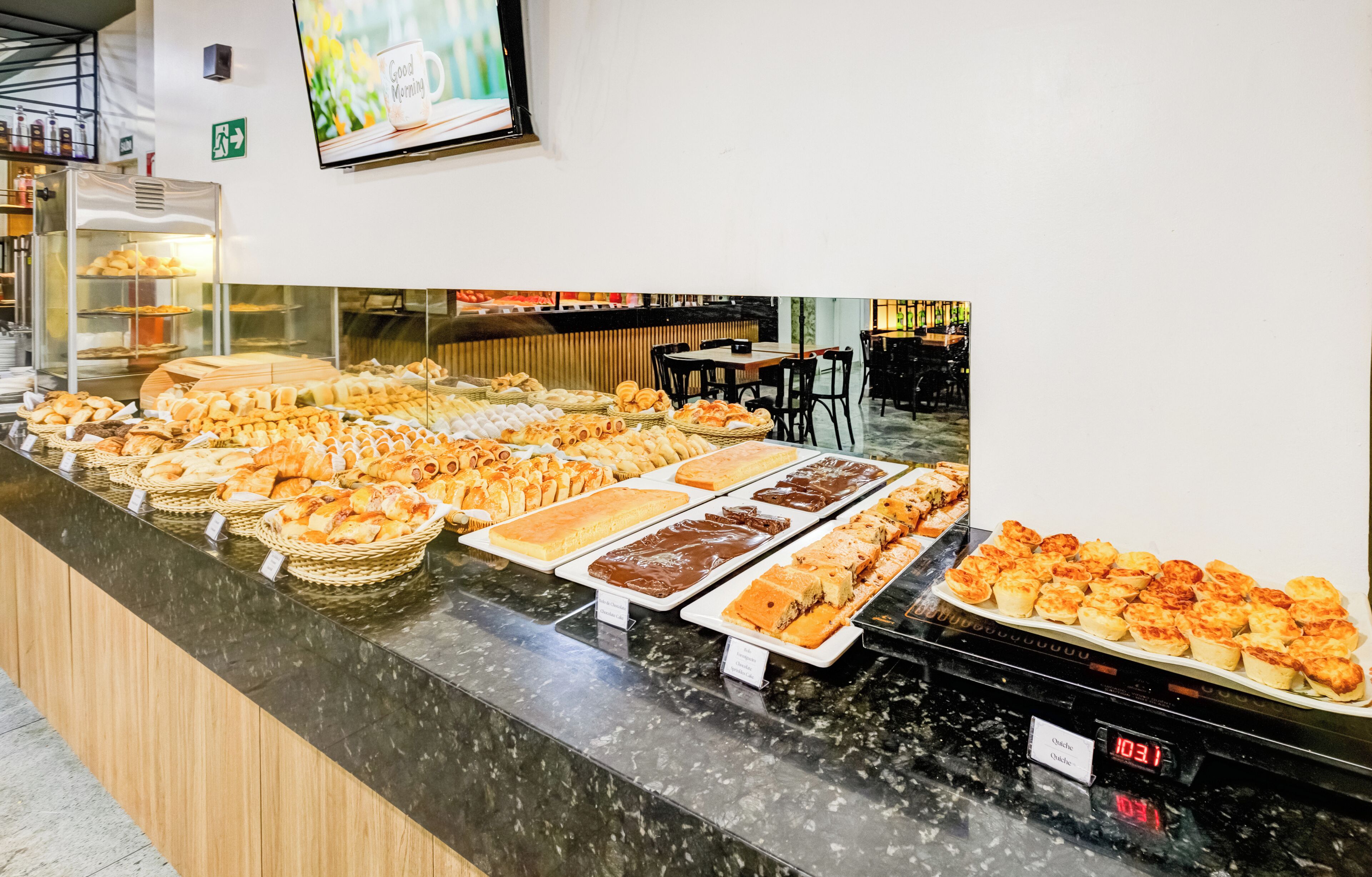 A buffet counter with various baked goods and pastries.