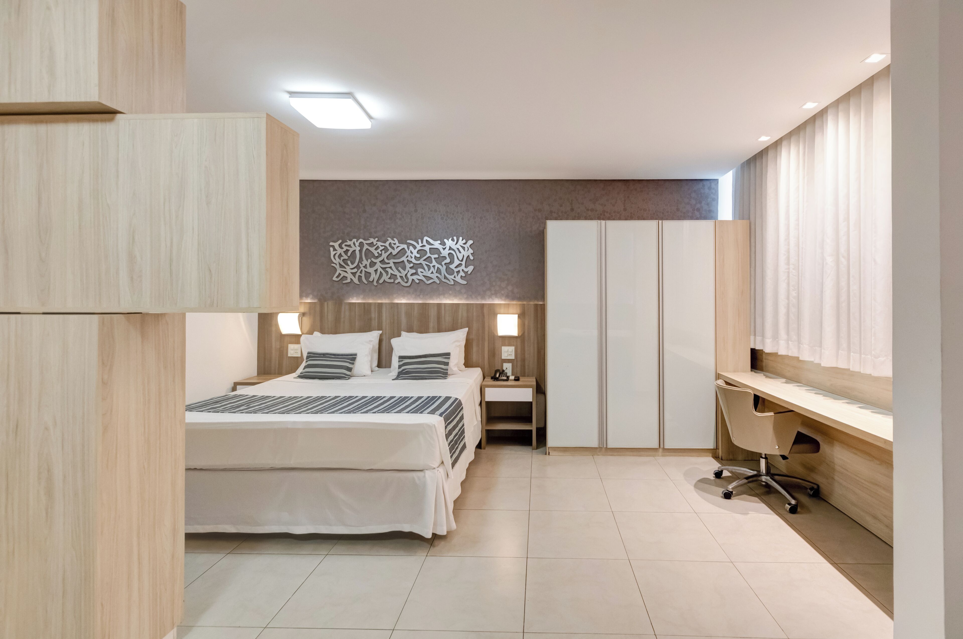 Una moderna camera d'hotel con letto, comodino, scrivania, sedia, armadio e decorazioni a parete.