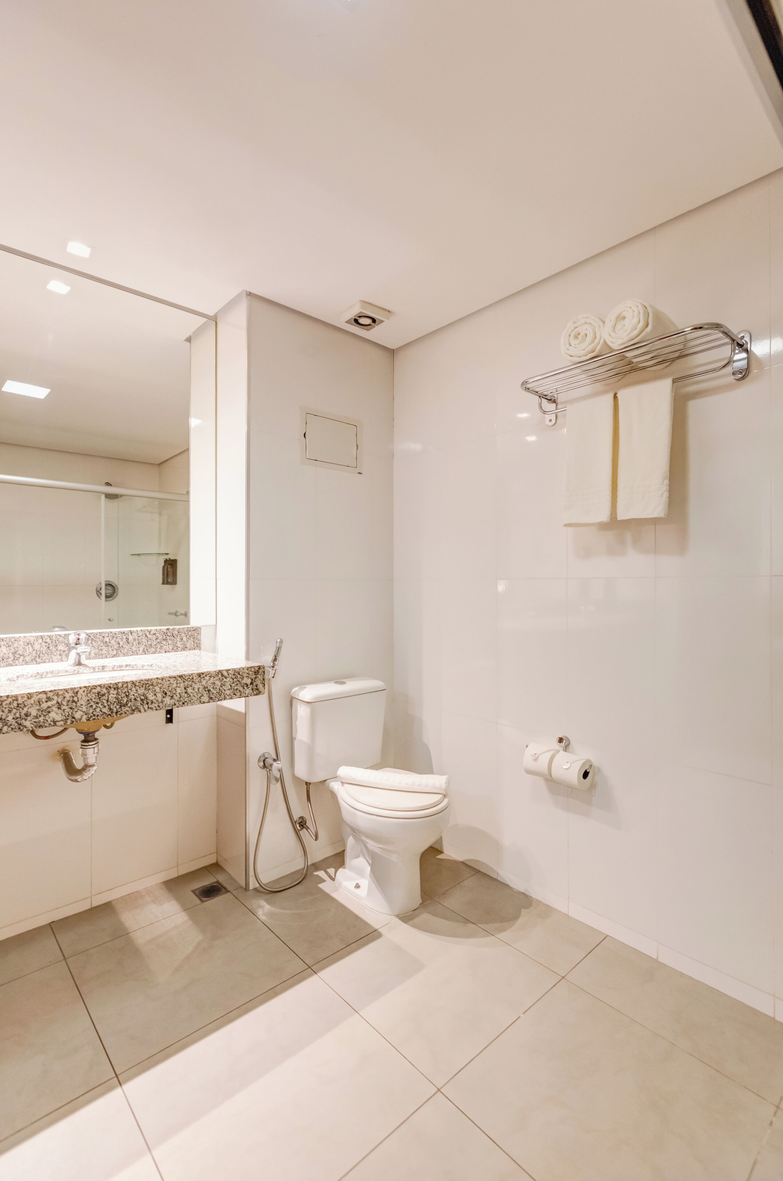 Un baño moderno con inodoro, lavamanos y toallero.