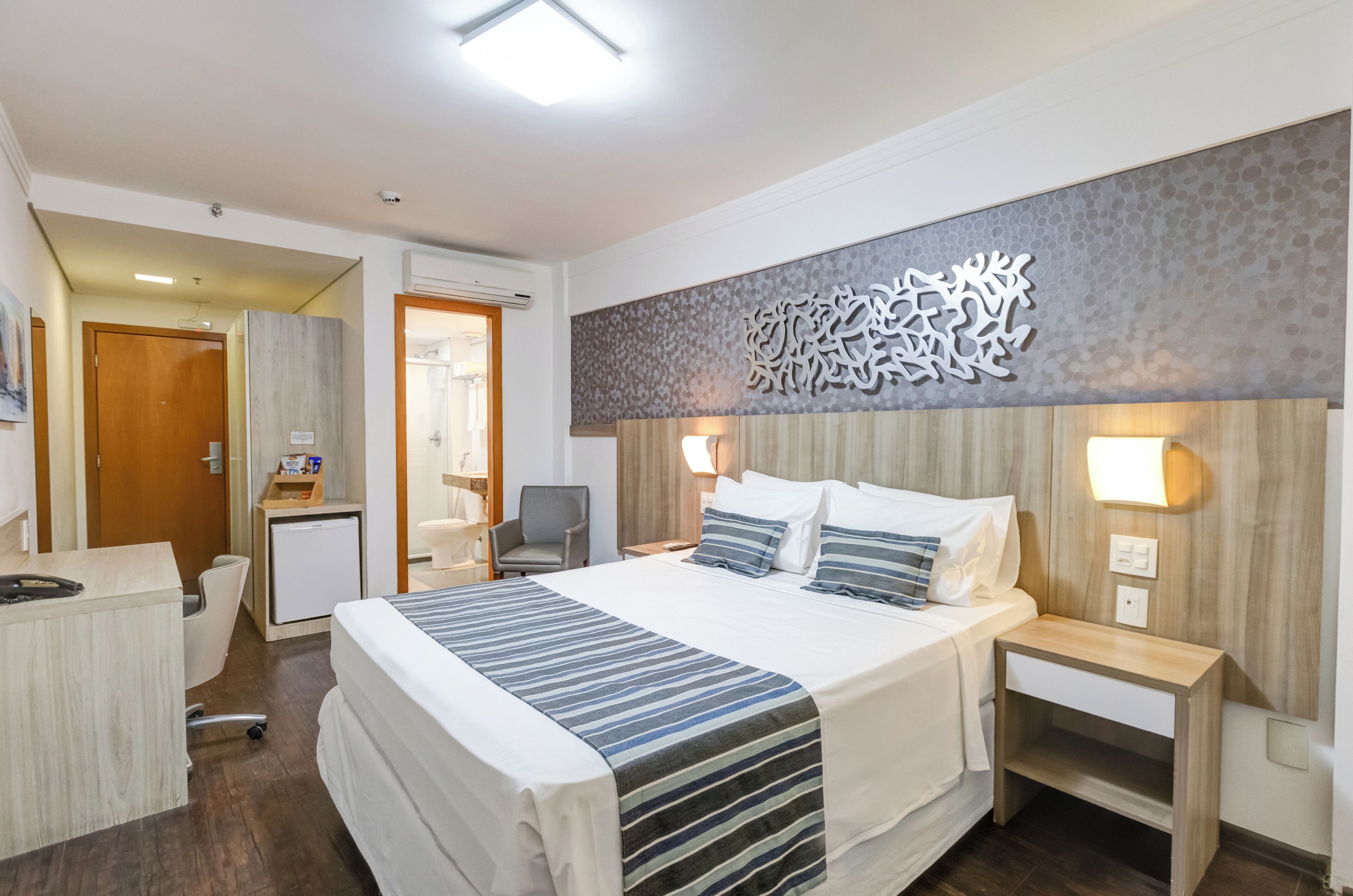 Een hotelkamer met een groot bed, nachtkastjes, een bureau en een stoel.