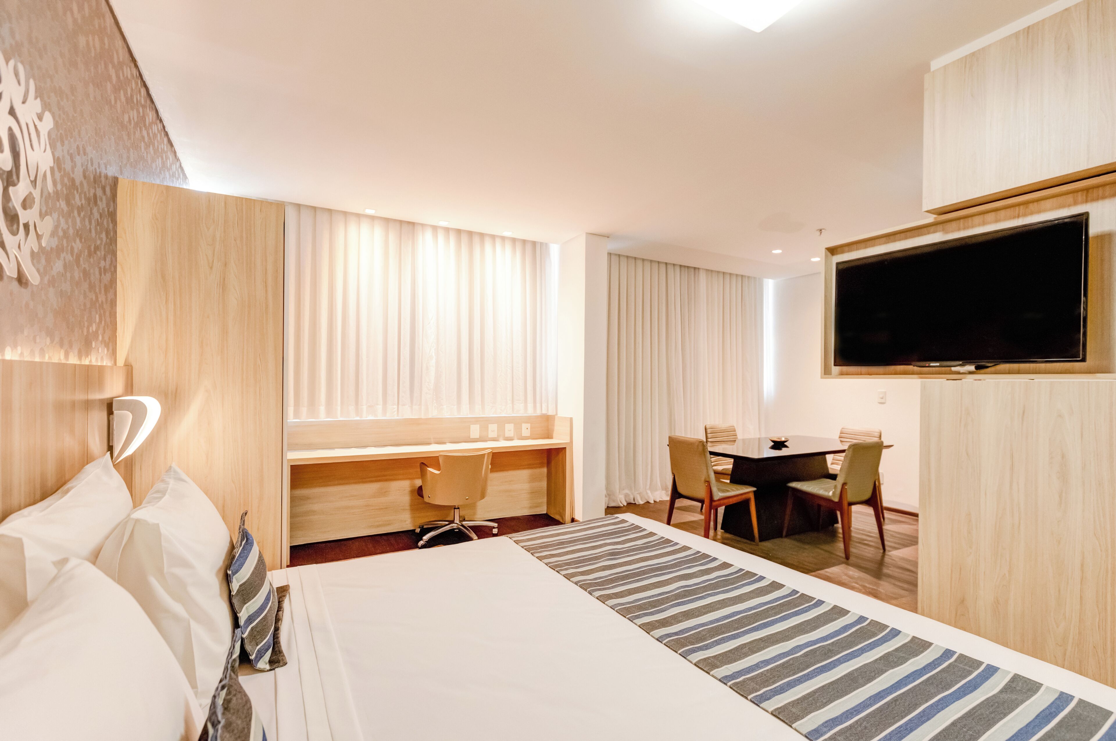 Une chambre d’hôtel équipée d’un lit, d’un bureau, d’une télévision et d’un coin repas.