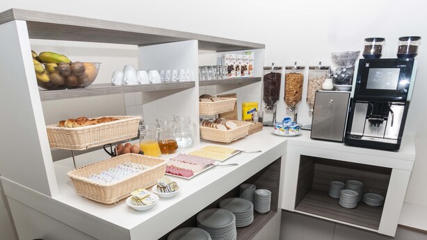 A breakfast buffet with various food items, baskets, and a coffee machine. - Hotel Fine Harmony (Amsterdam)