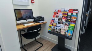 A desk with a computer, a printer, and a bulletin board with various travel brochures. - Hotel Fine Harmony (Amsterdam)