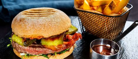 A burger with fries and ketchup on a slate surface.