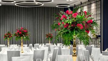 Un salón de banquetes con mesas redondas dispuestas para comer, con manteles blancos y centros de mesa dorados.