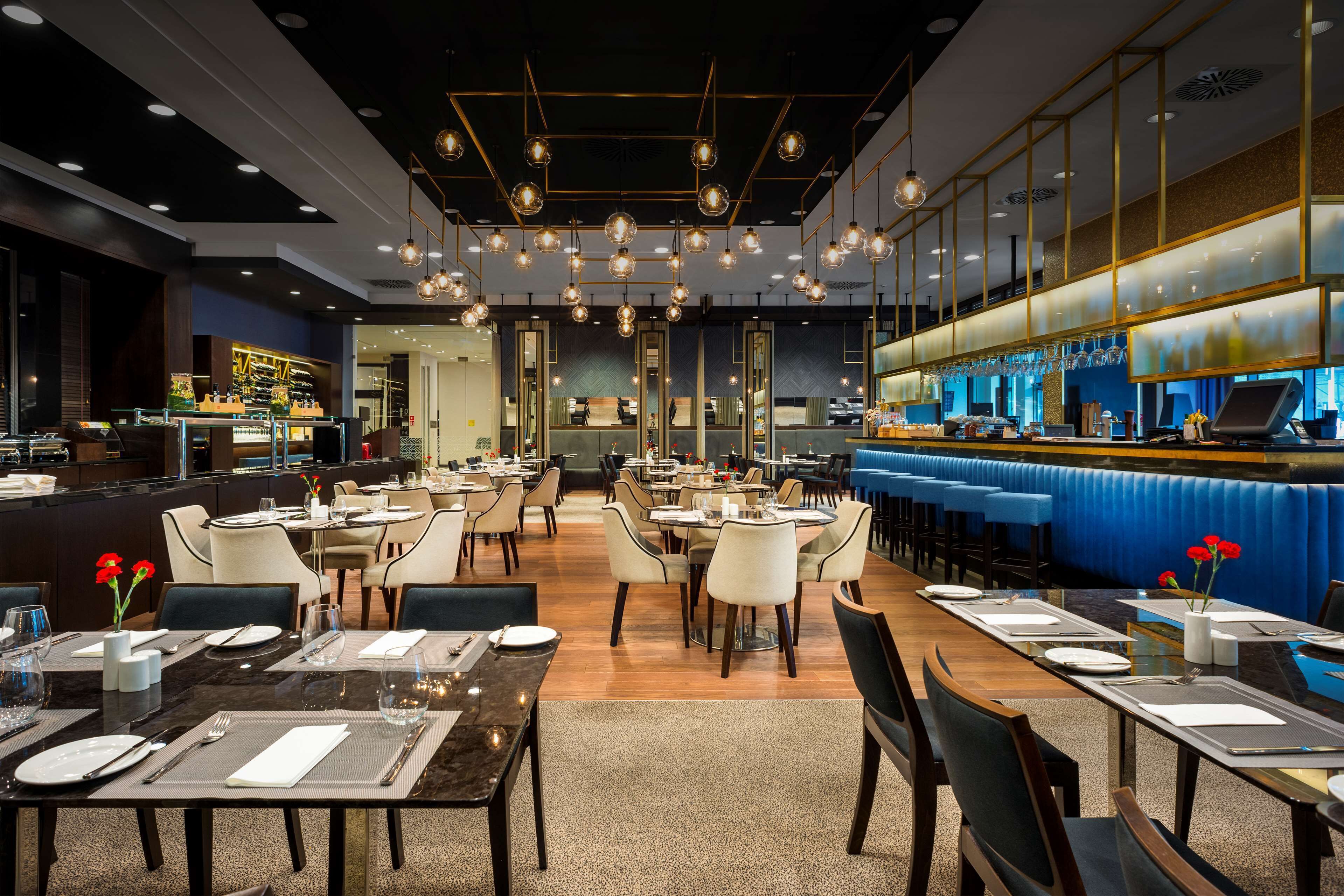 Un restaurant moderne doté de plusieurs espaces de restauration, d’un bar et d’un comptoir avec un coin salon bleu et confortable.