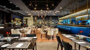 Un restaurant moderne doté de plusieurs espaces de restauration, d’un bar et d’un comptoir avec un coin salon bleu et confortable.