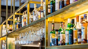 A bar with shelves stocked with various liquor bottles and a rack of glasses.