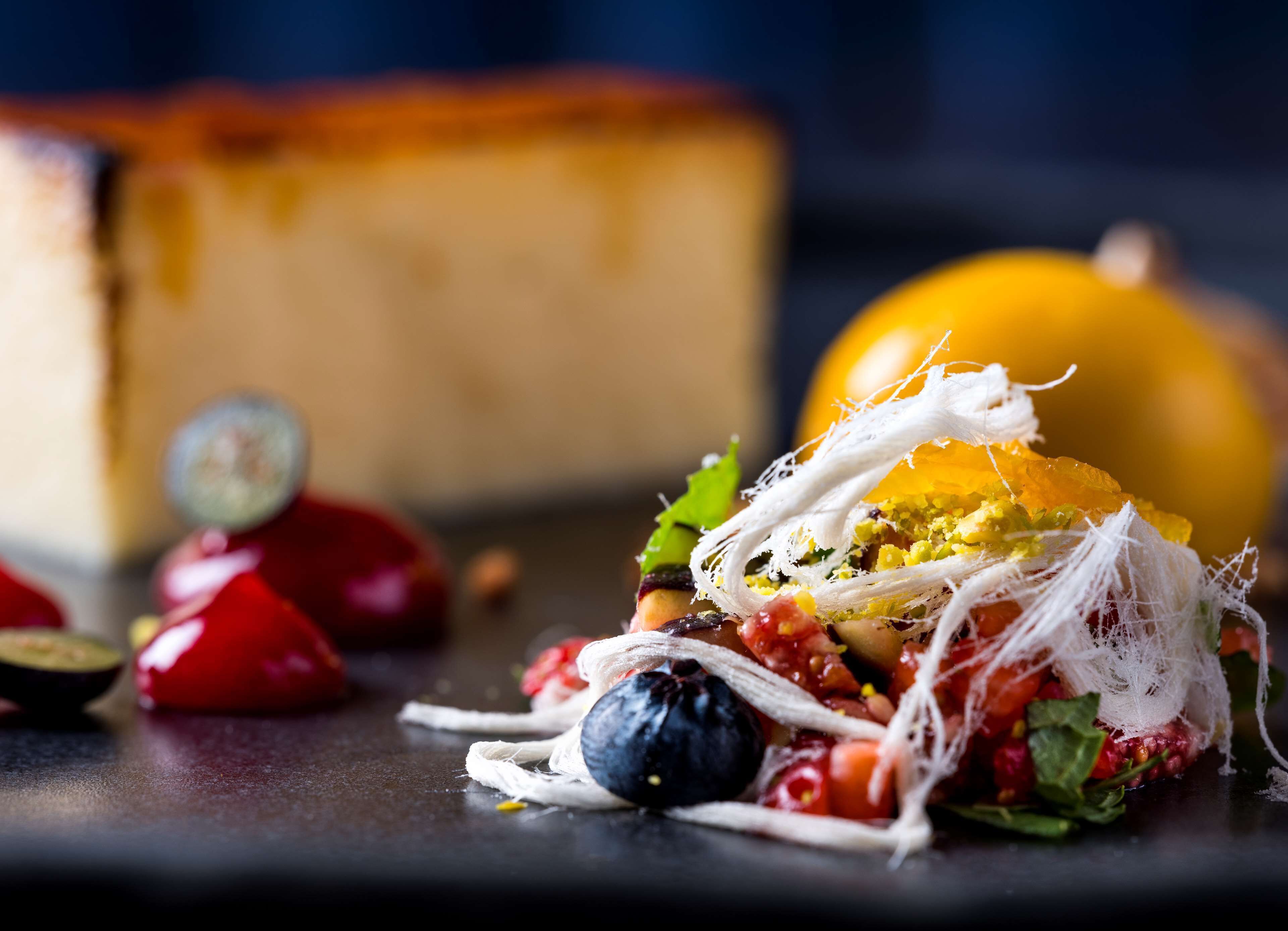 Un postre con fruta y un pastel de queso al fondo.