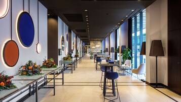 Eine moderne Hotelhalle mit einer langen Rezeption, einer Sitzgelegenheit und großen Fenstern.