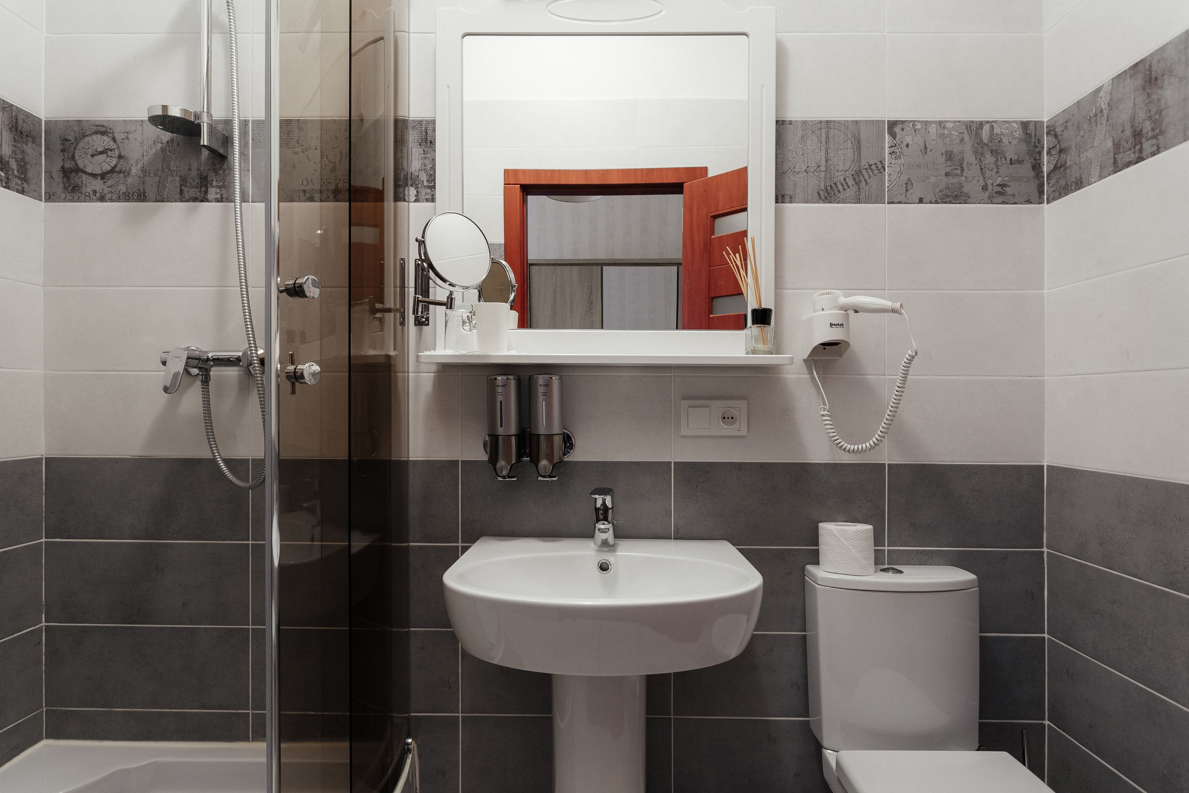 A modern bathroom with a glass-enclosed shower, a white sink, and a toilet.