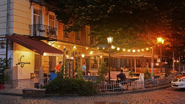 A cobblestone street with outdoor seating at a restaurant. - Ribas (Odesa)