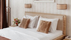 A neatly made bed with white and brown bedding, a wooden headboard, and two bedside lamps. - Ribas (Odesa)
