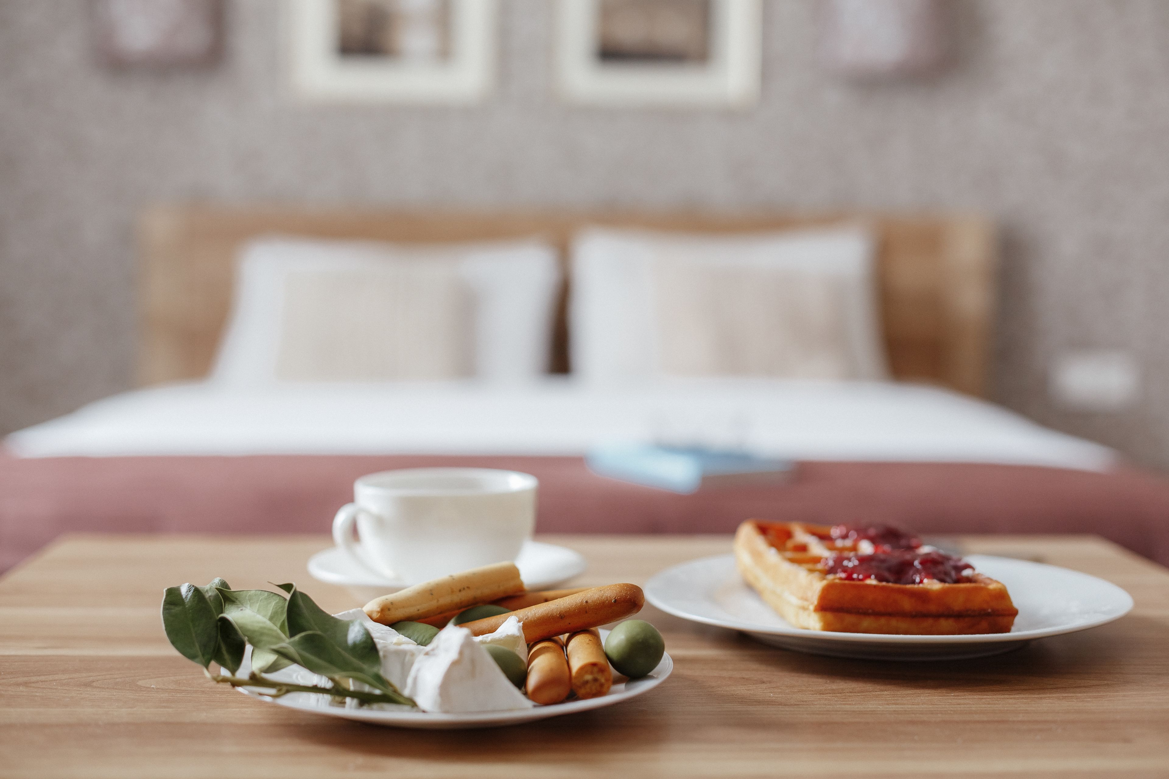 A breakfast setting with a plate of croissants, a cup of coffee, and a plate of waffles with jam.