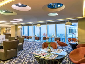 Un moderno vestíbulo de hotel con techos altos, grandes ventanales que ofrecen vistas a la ciudad y muebles contemporáneos.
