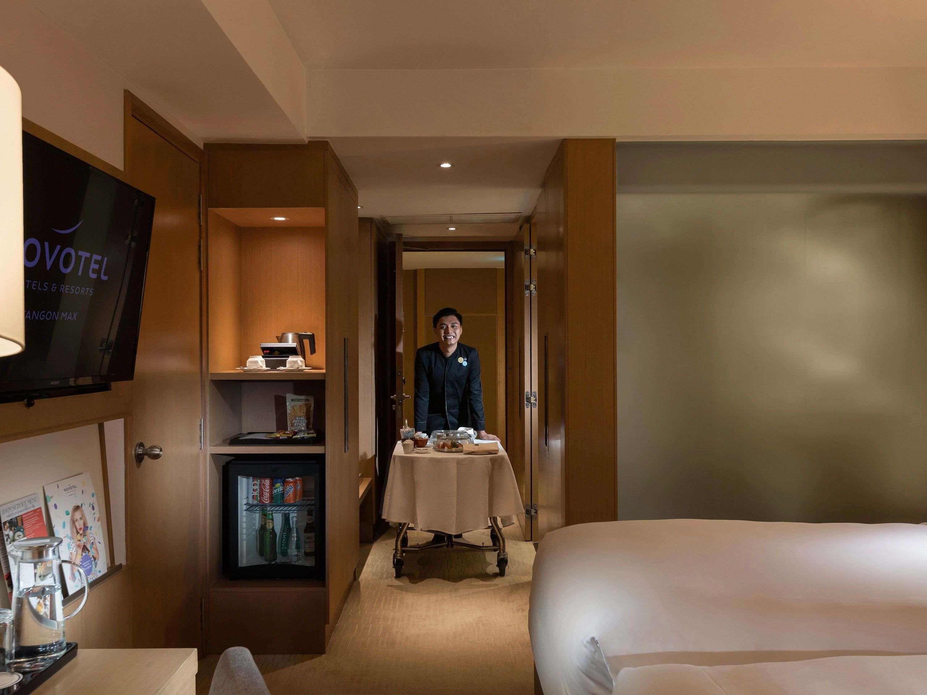 Ein Hotelzimmer mit einem Bett, einem Schreibtisch mit Kaffeemaschine, einem Fernseher und einer Minibar.
