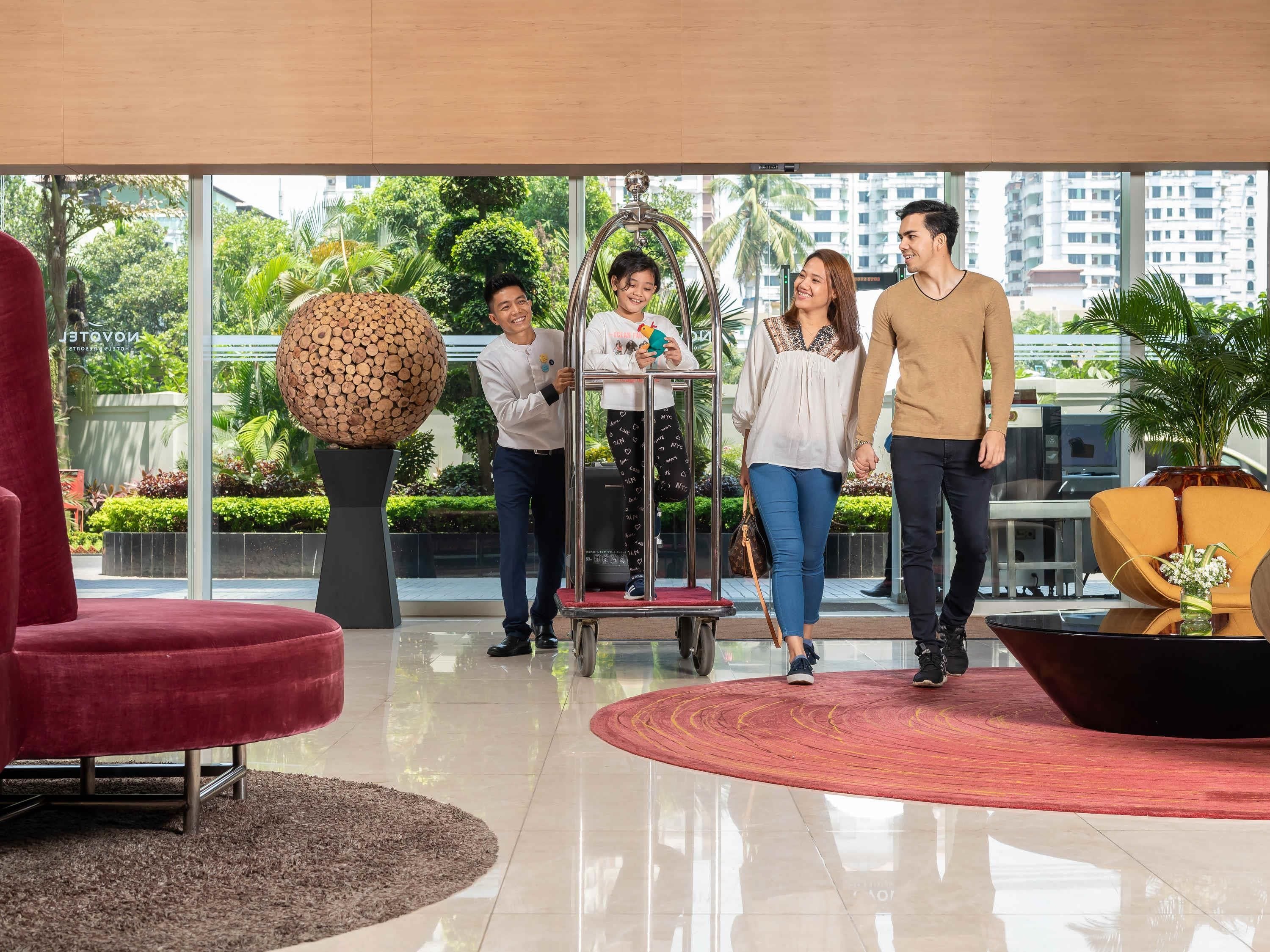 A modern lobby with a glass wall, a red chair, a large spherical sculpture, and a coffee table with a plant.