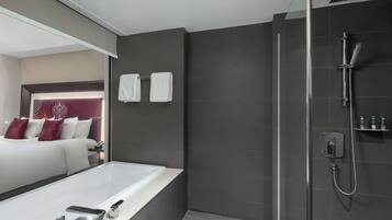 Un baño moderno con una bañera grande, ducha y tocador con espejo.