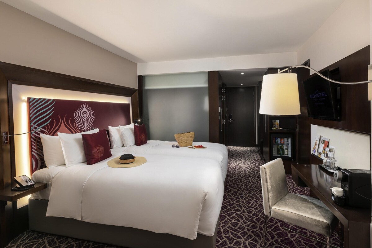 Habitación de hotel con una cama grande, un escritorio con lámpara, un televisor y un mini bar.