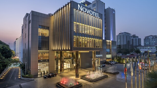 A modern hotel with a prominent 'Novotel' sign, a spacious entrance, and a fountain display.
