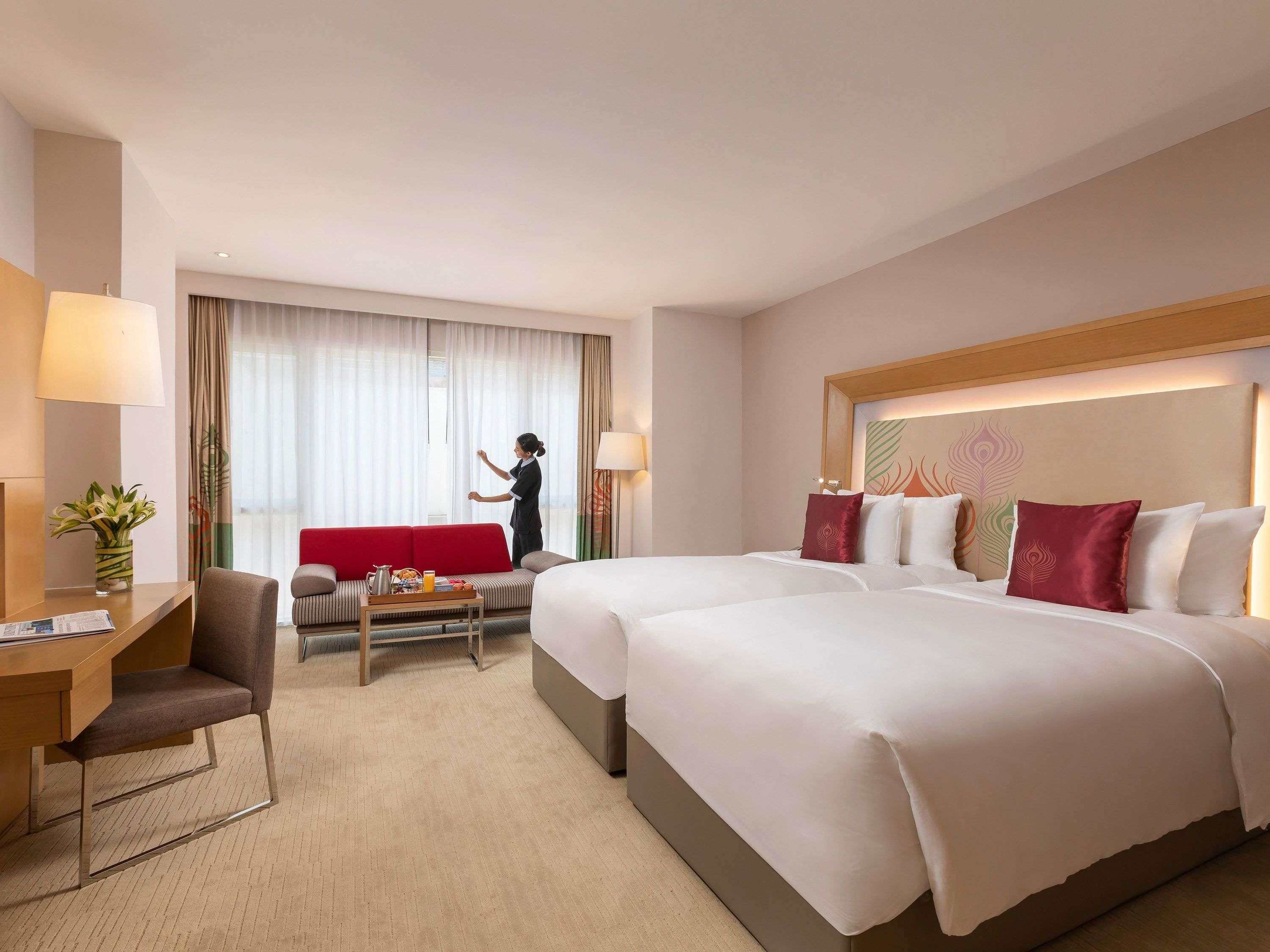 A hotel room with a bed, a sofa, a desk, and a chair.