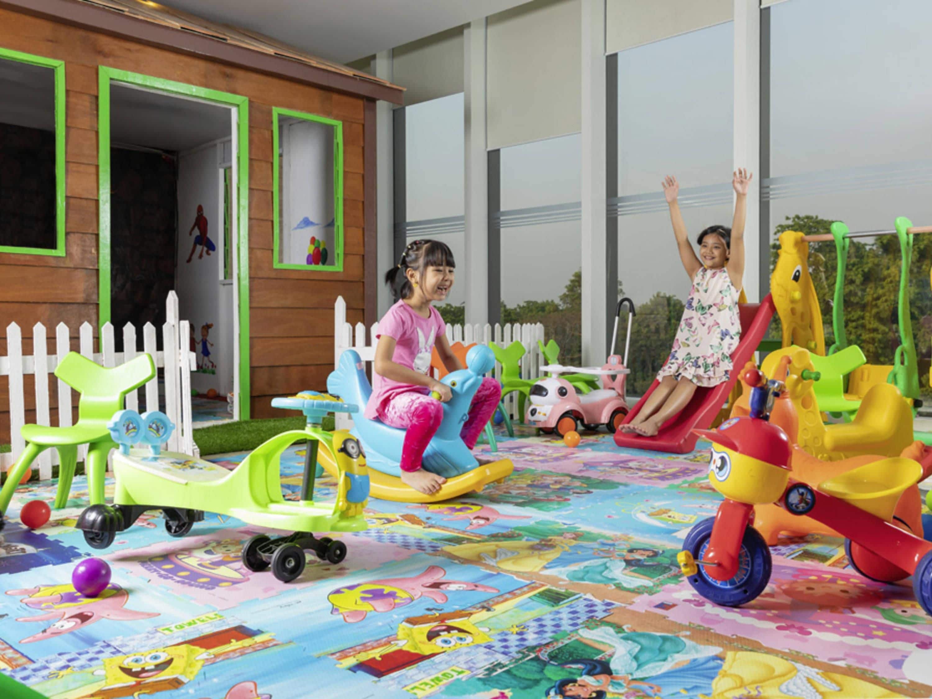 A play area with children's rides and a white picket fence.