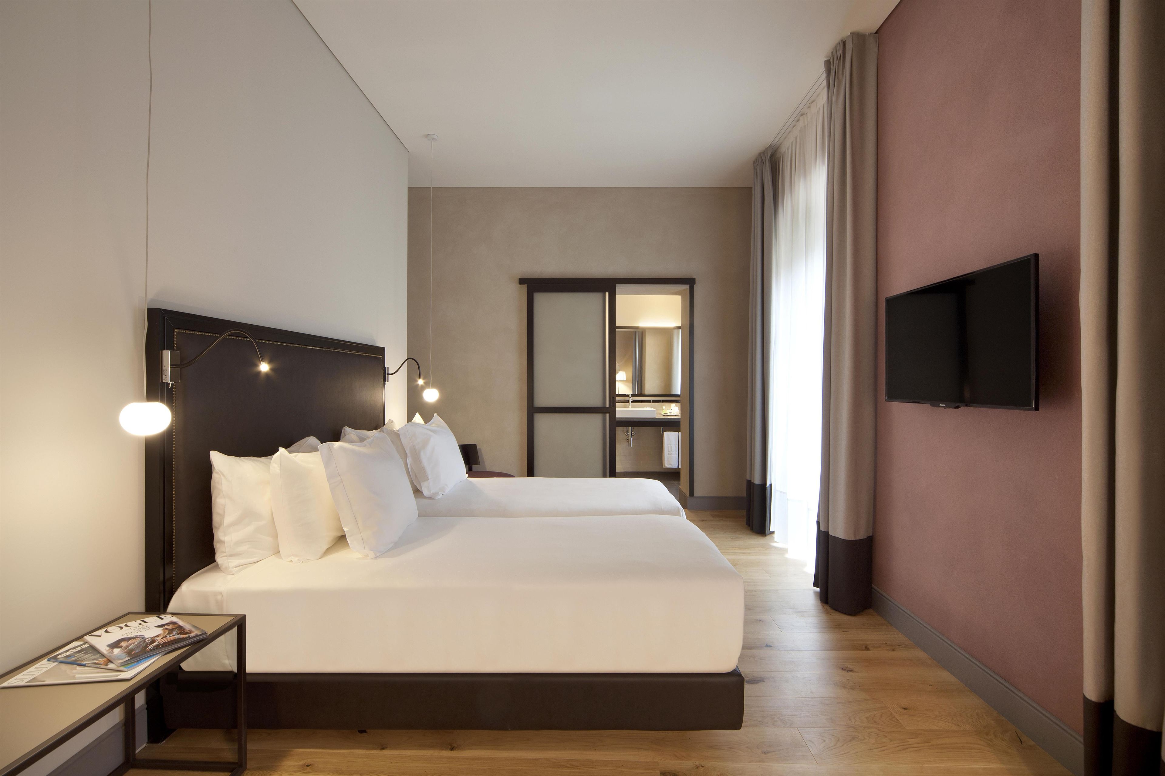 Una camera d'albergo con un letto grande, comodini, una televisione a schermo piatto e uno specchio.
