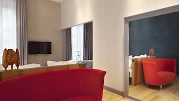 Una habitación de hotel moderna con un espejo grande, un sofá rojo, un tocador de madera y un televisor de pantalla plana montado en la pared.
