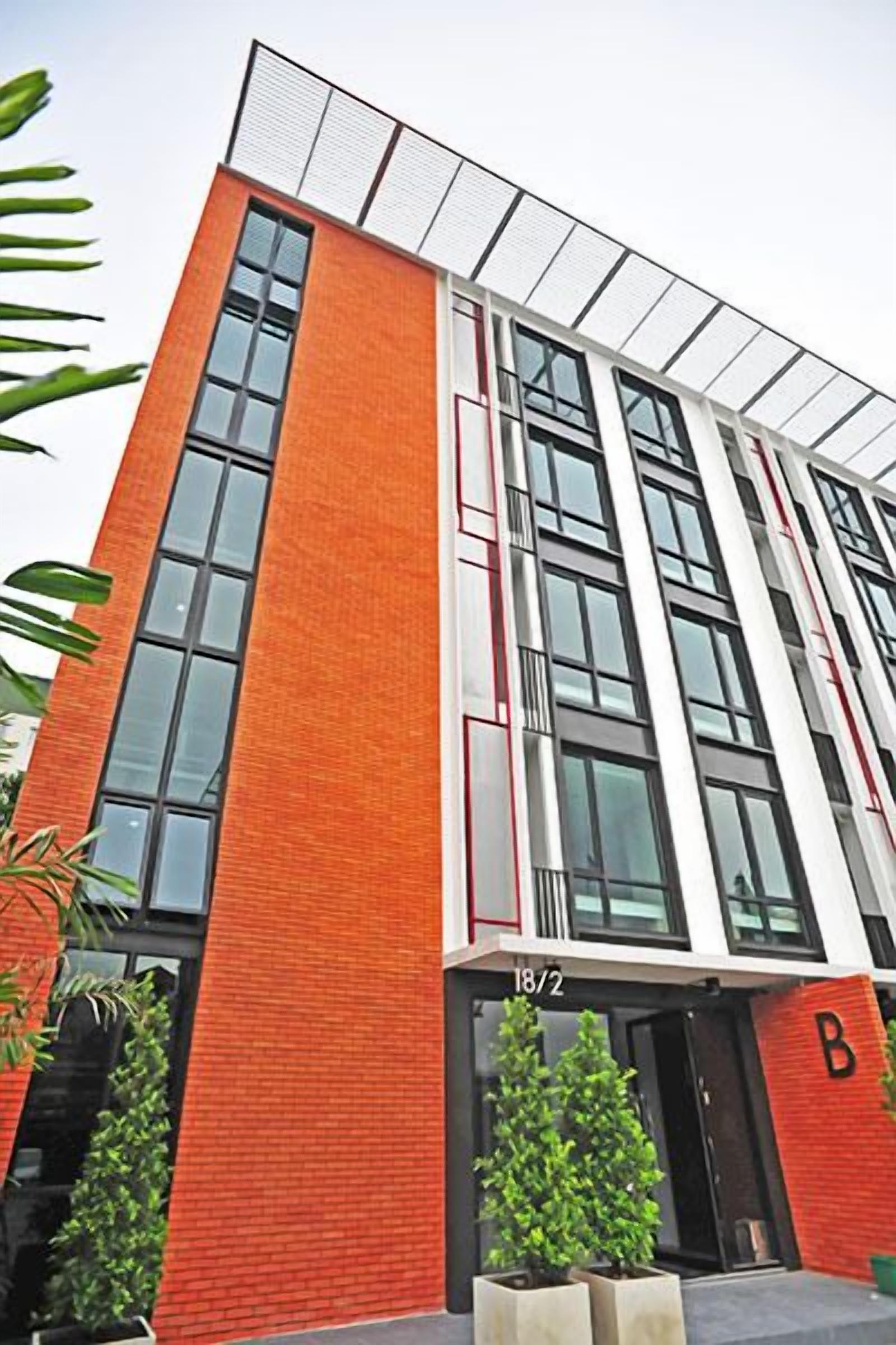 A modern building with a red brick facade, large windows, and a flat roof.