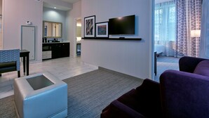 A modern hotel room with a living area, a dining area, and a bedroom.