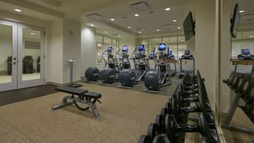 Un gimnasio con cintas de correr, máquinas de pesas y pesas sueltas.
