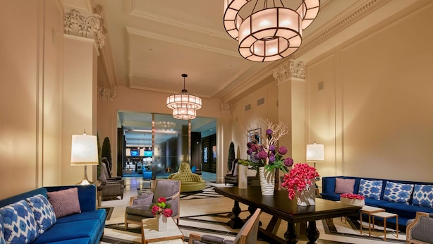 A spacious lobby with a blue sofa, a wooden coffee table, and a chandelier.
