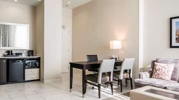 Una habitación de hotel moderna con zona de comedor, kitchenette y espacio de estar.