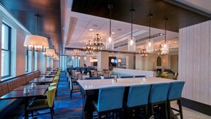A hotel dining area with long tables, booths, and a bar.