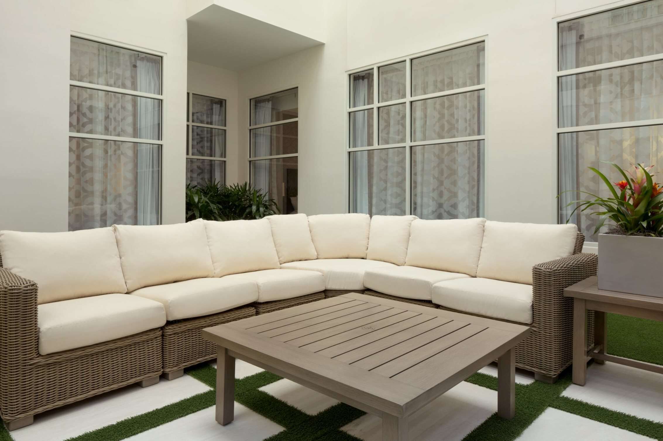 A sectional sofa with a woven frame, a wooden coffee table, and a potted plant.