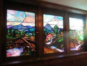 Três janelas de vitral com uma cena de paisagem.